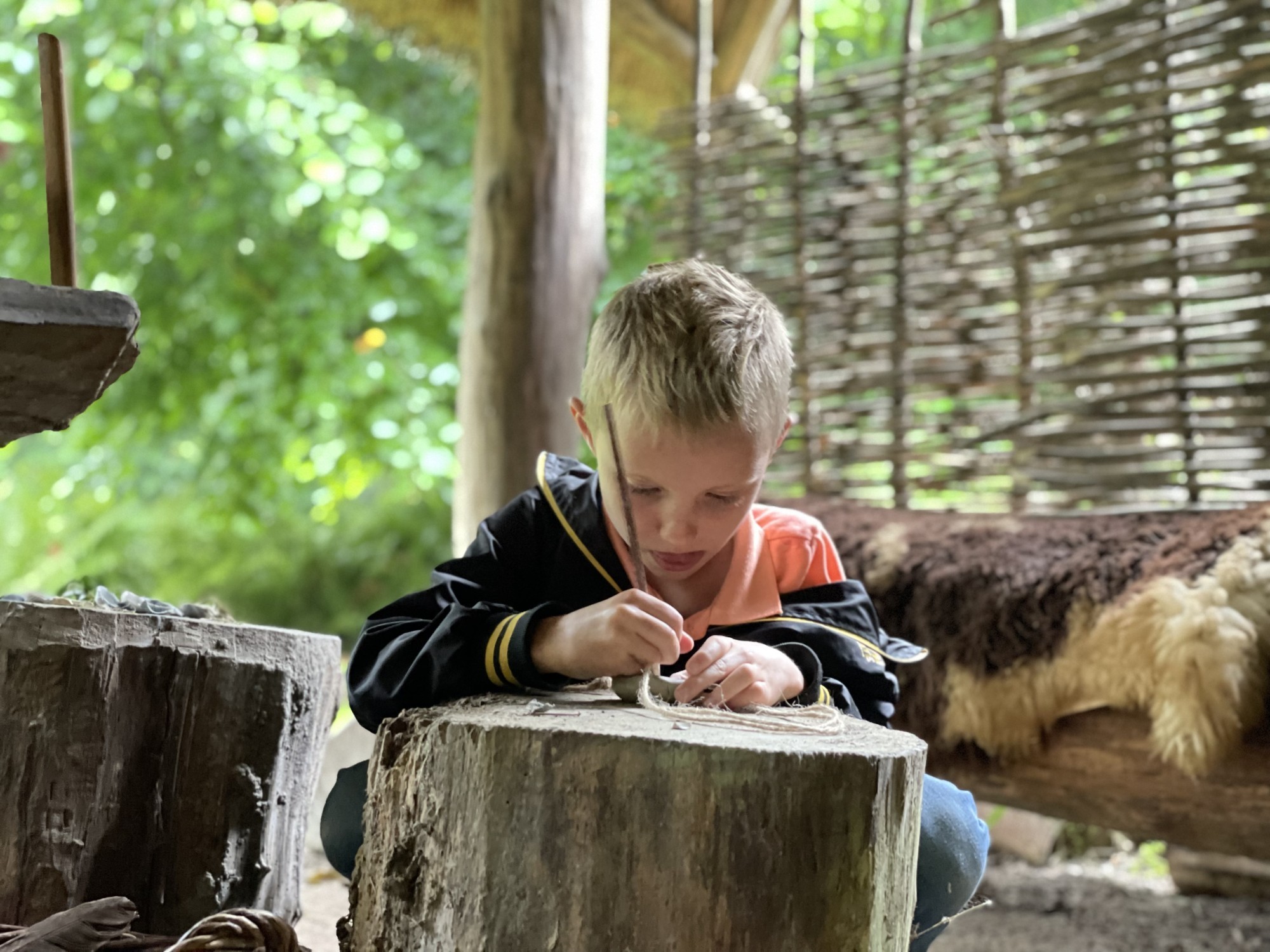 Kind maakt een klei ketting op de bronstijdboerderij