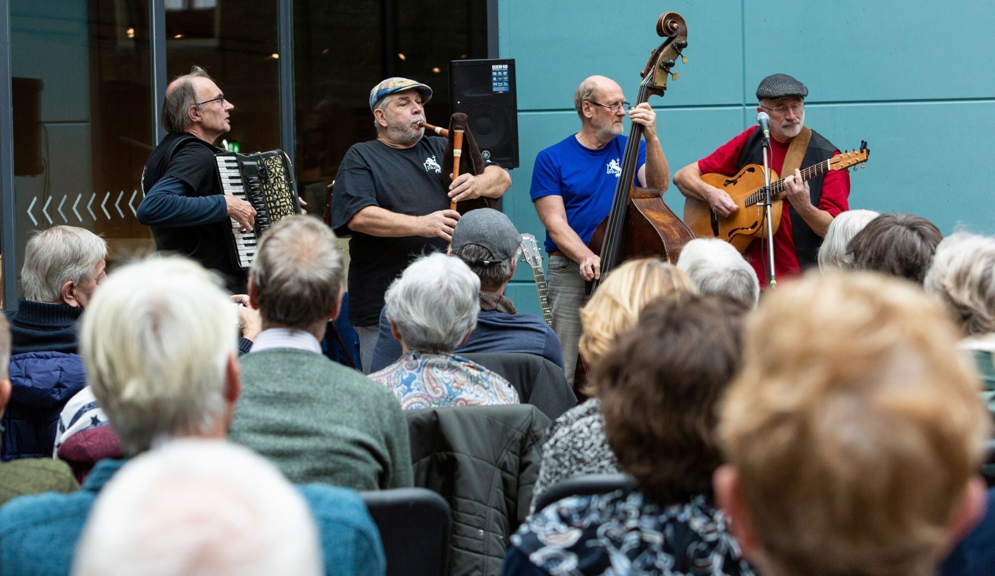 Sfeerbeeld van een huiskamerconcert, waar muzikanten hun instrumenten bespelen