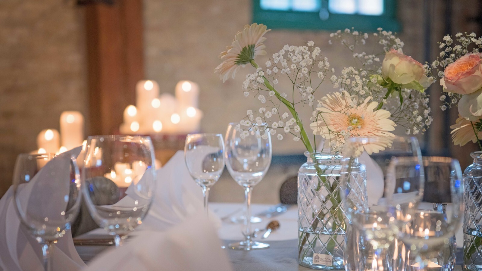 Tafel opgedekt voor bruiloft. Met bloemen, kaarsjes en wijnglazen.