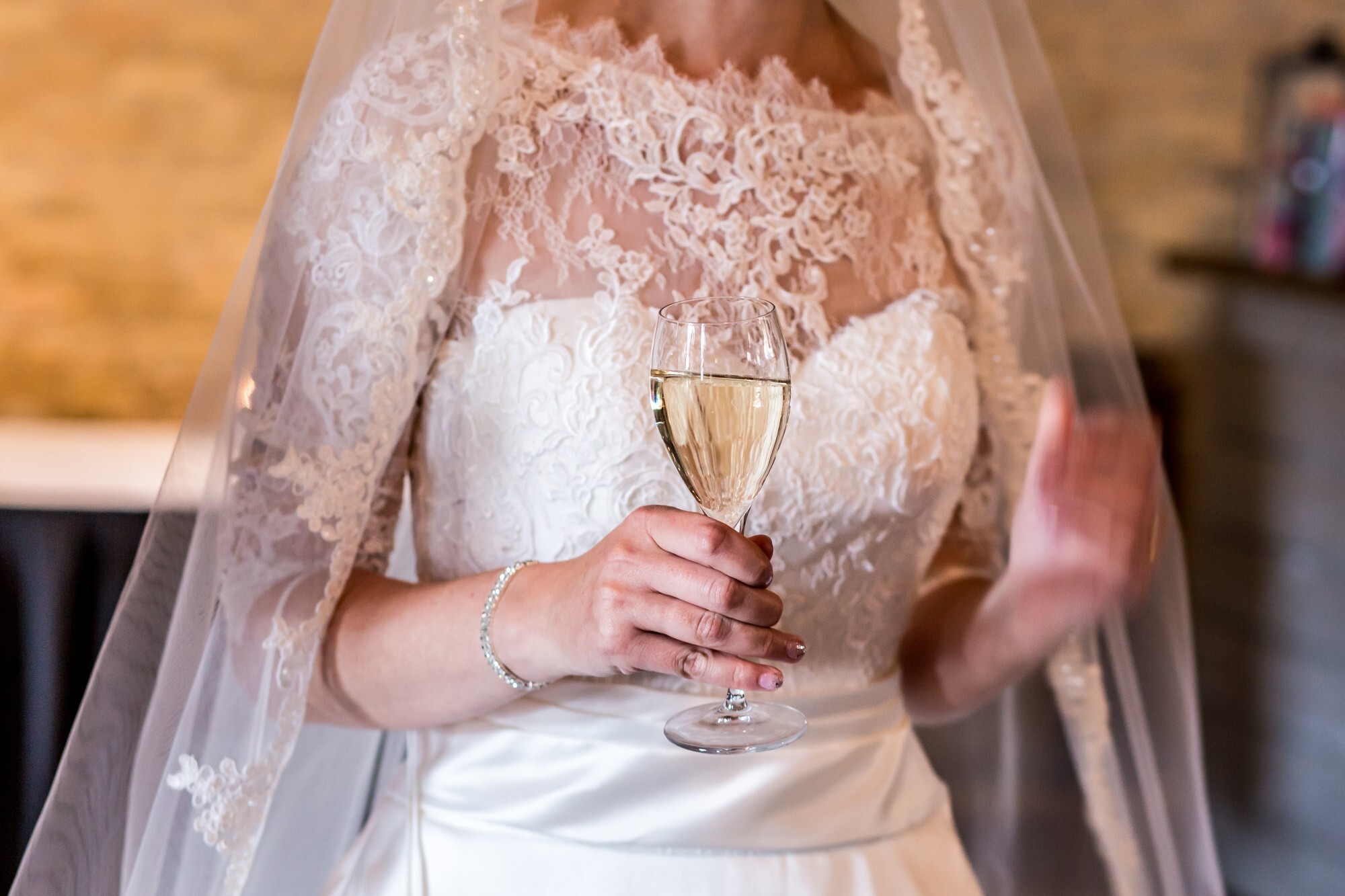 Bruid heeft een glas champagne in haar hand.
