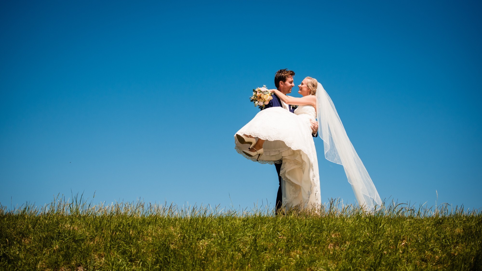 Bruidegom houdt de bruid in zijn armen op de dijk
