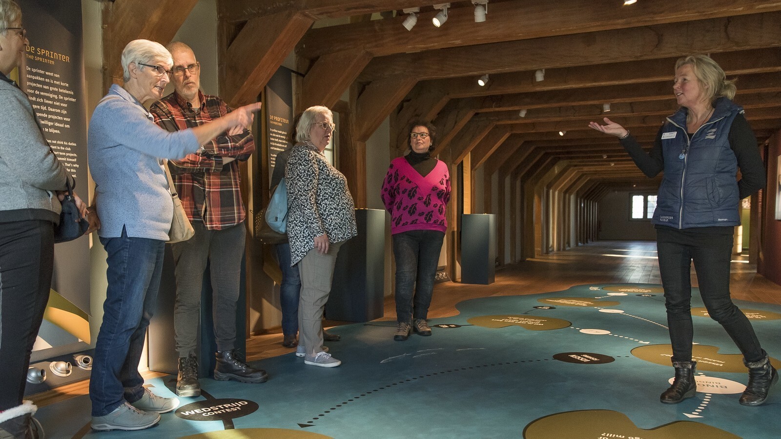 De groep krijgt tijdens een rondleiding uitleg van een museumdocent.