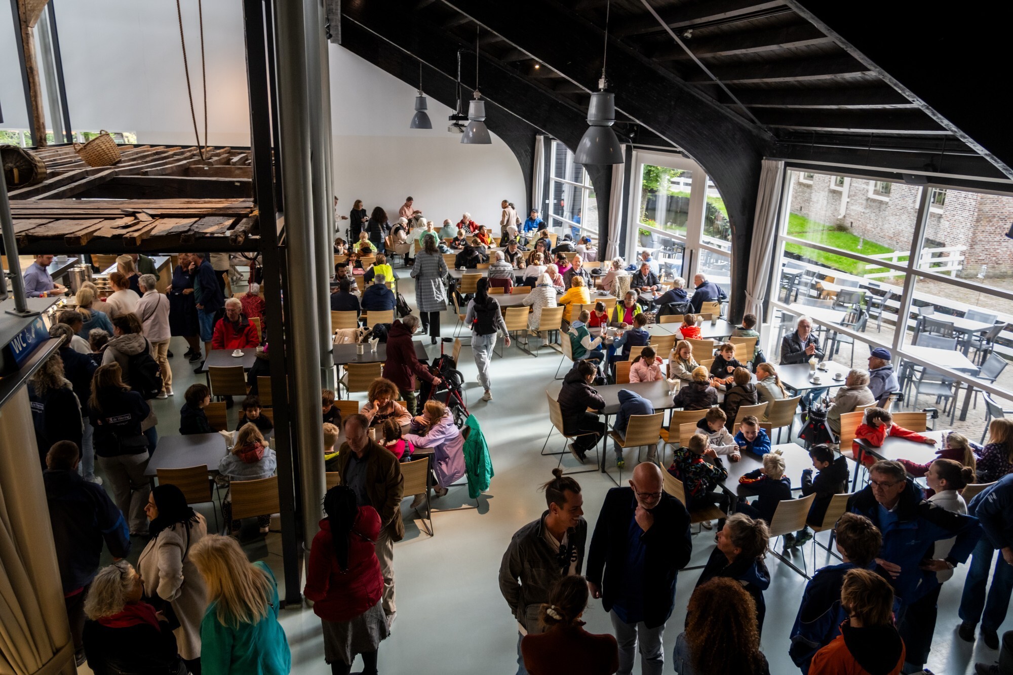 Het Amsterdamse huis van binnen, met mensen die aan het rondlopen zijn.