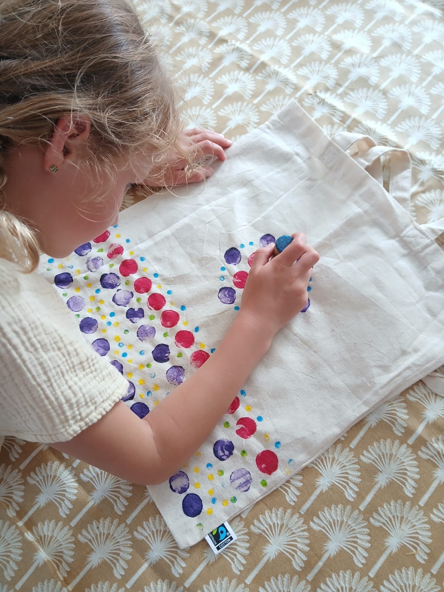 Meisje is met verf stippen aan het zetten op een linnen tas