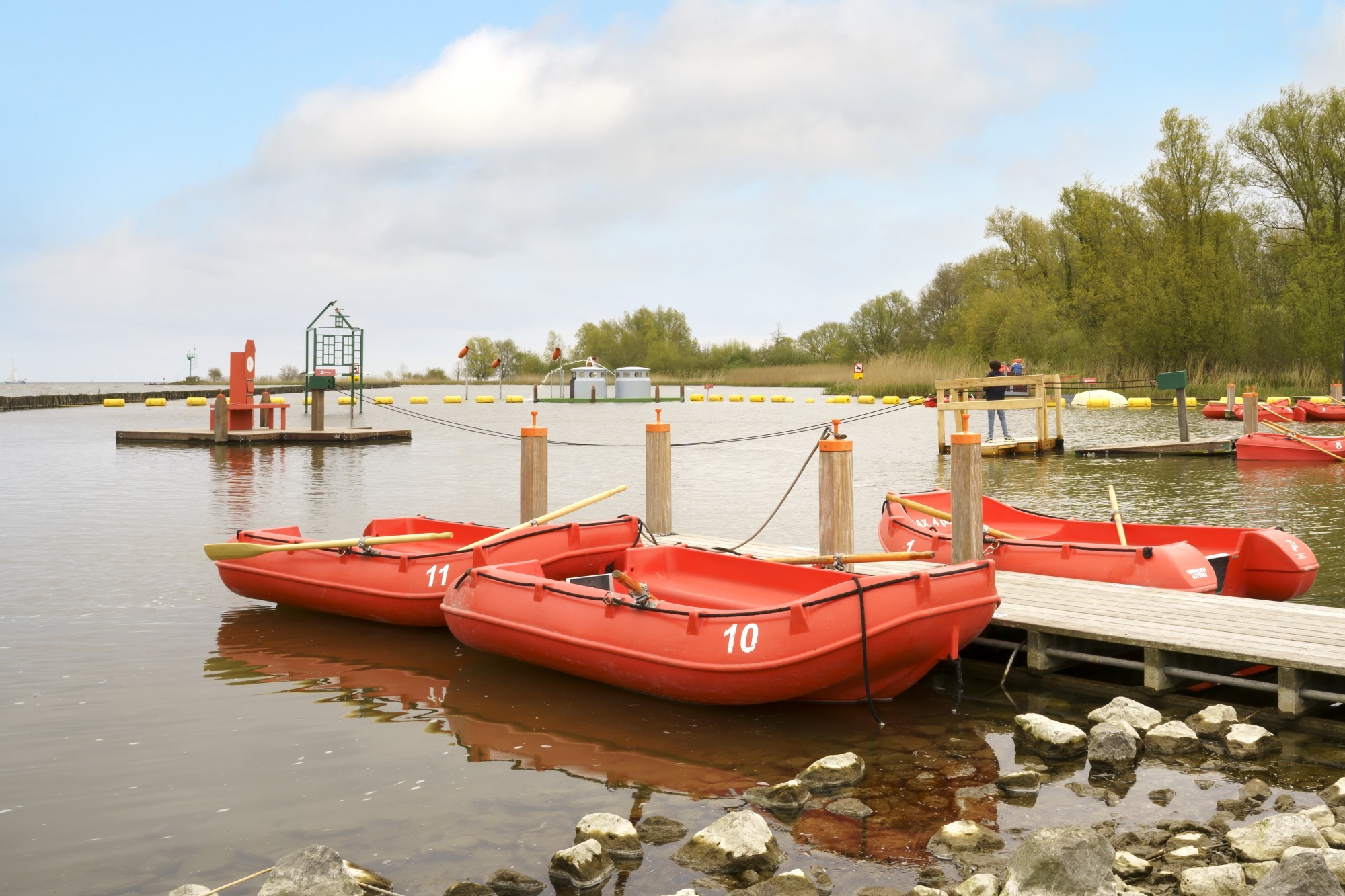 Meerdere rode roeibootjes liggen op het water.