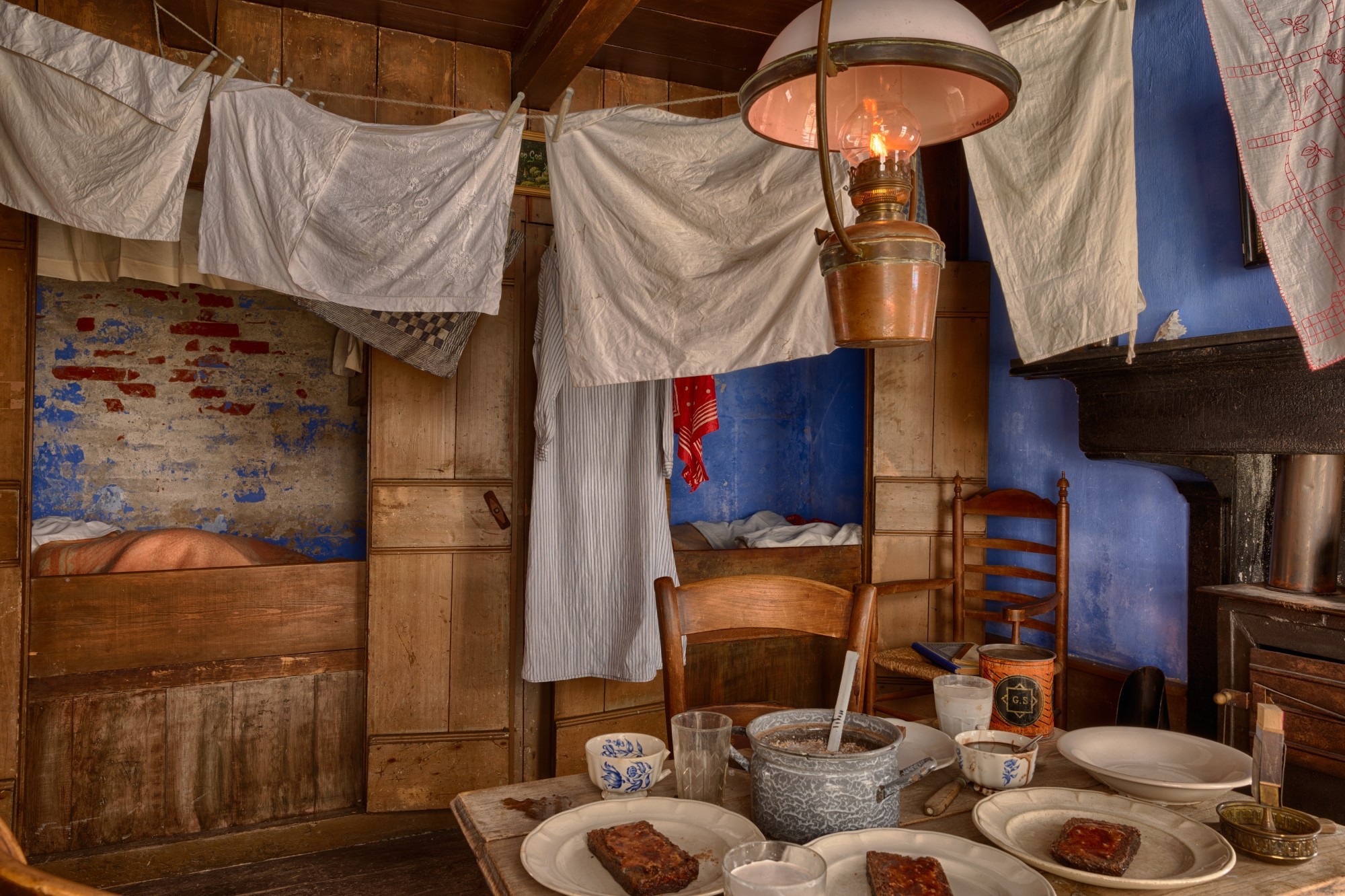 Twee bedsteden, de muur is afgebrokkeld en het verf is op verschillende plekken weg.