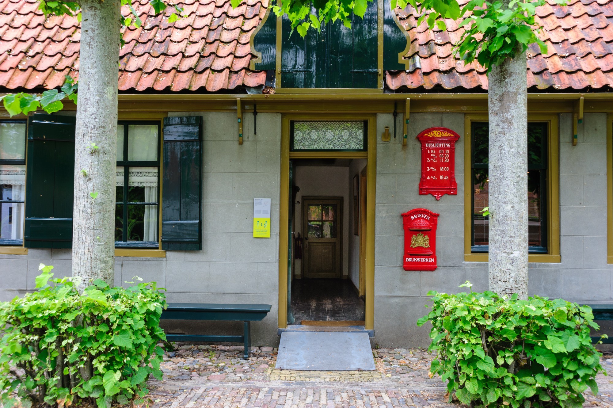 De deur van het postkantoor staat open, vanuit de gang kan je een kast zien.