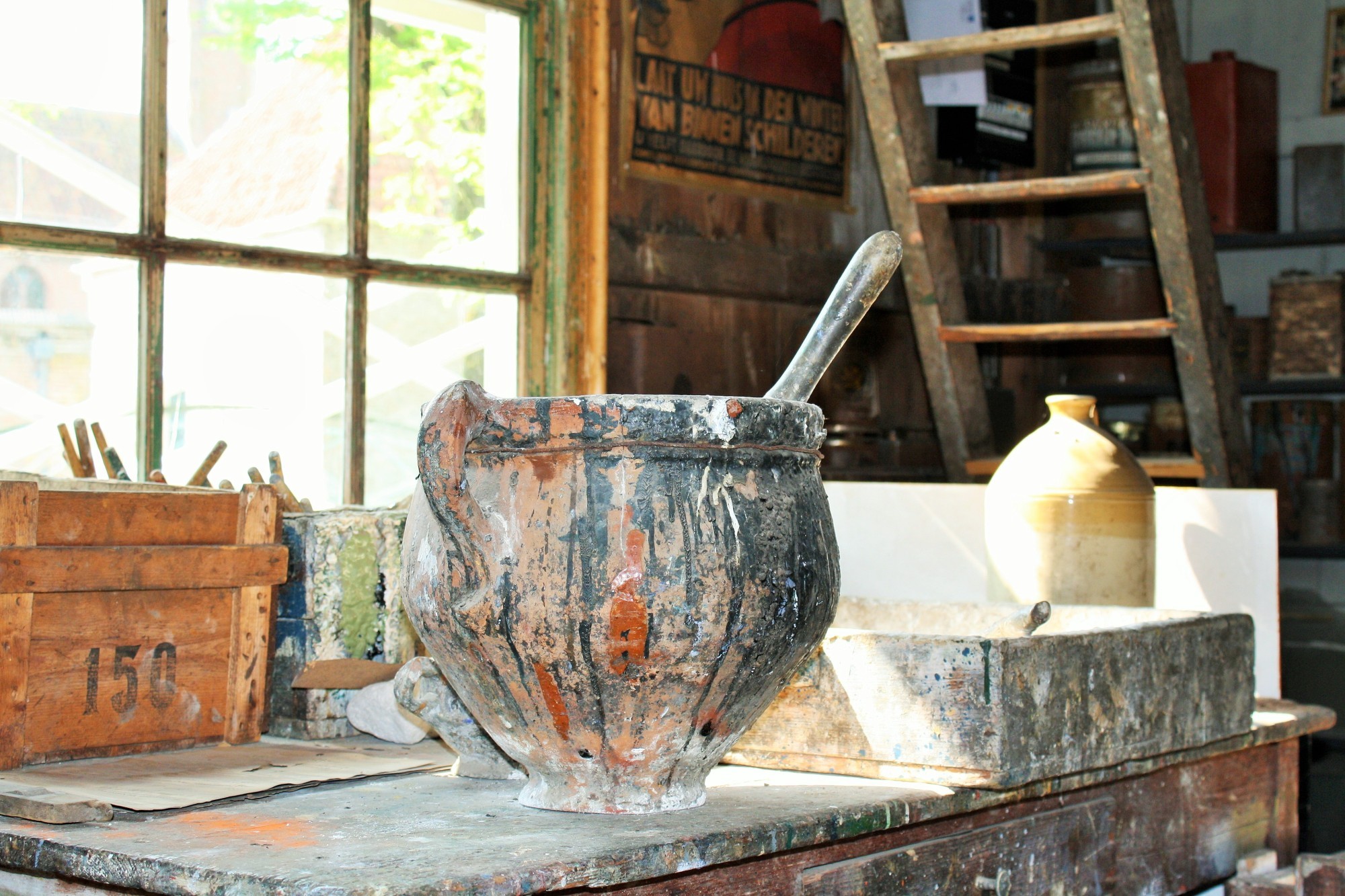 Een pot die onder het verf zit, een kwast steekt er boven uit