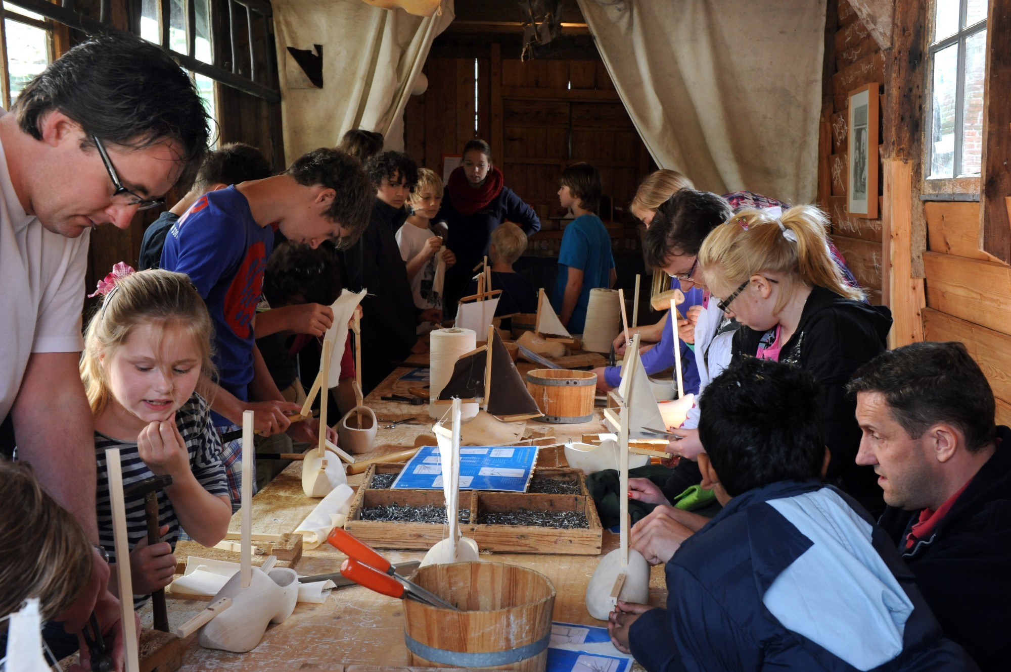 Kinderen en ouders maken een klompbootje