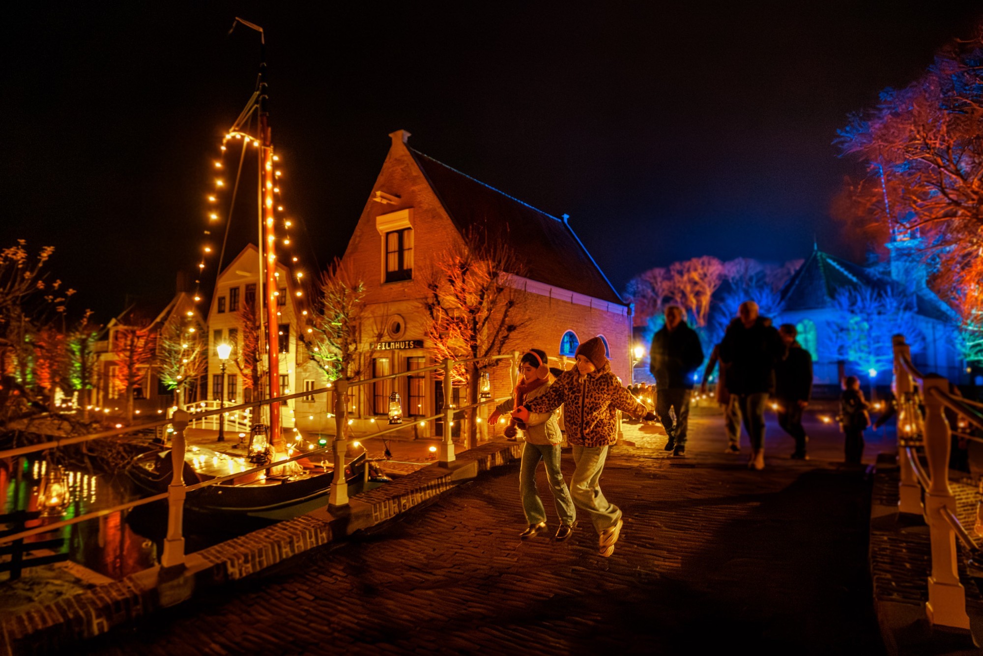 Kinderen lopen over de sfeervol verlichte brug tijdens Zuiderzeelicht